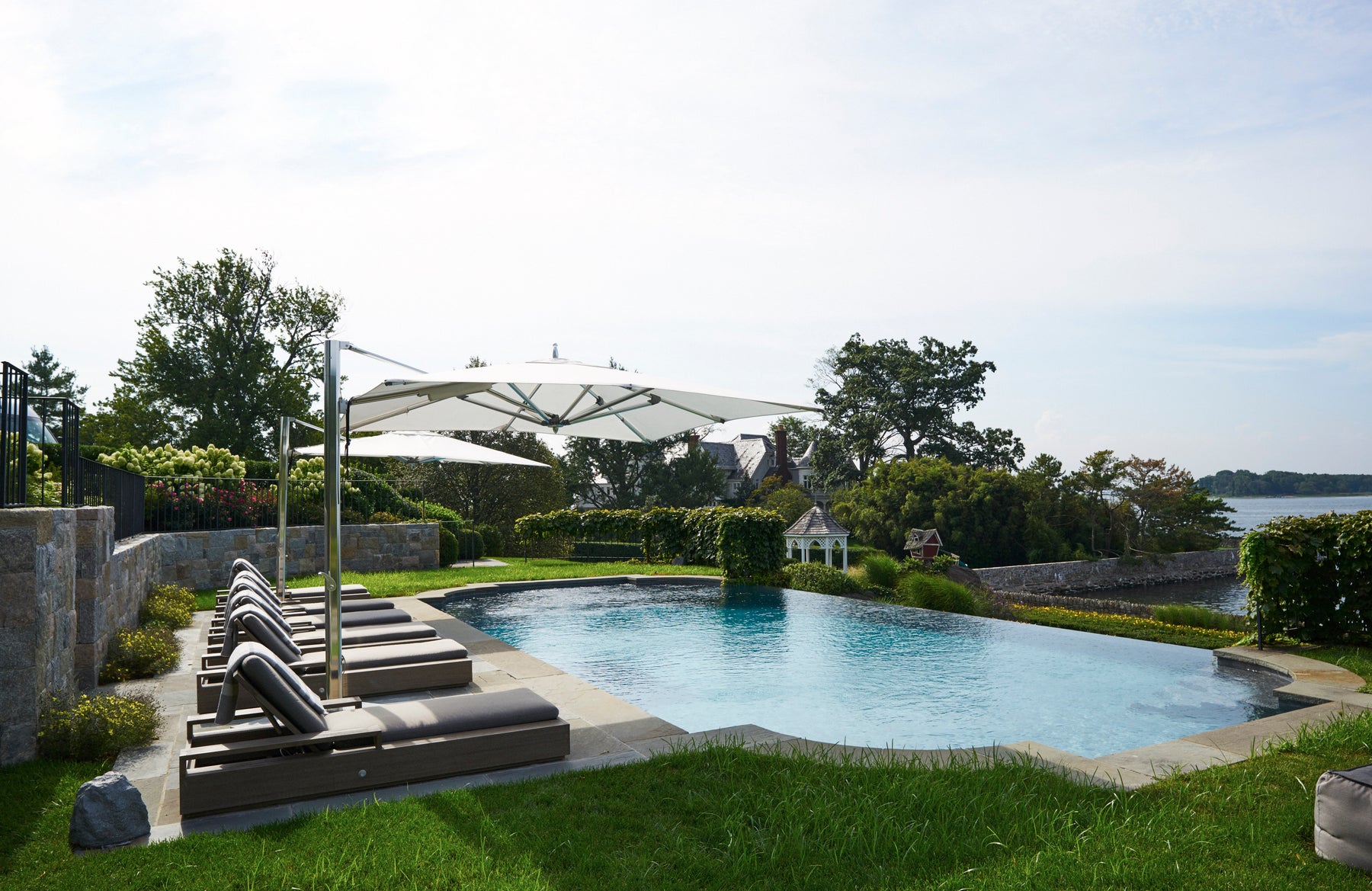 Teak lounge chairs by the infinity pool- modern luxury interior design by Mar Silver